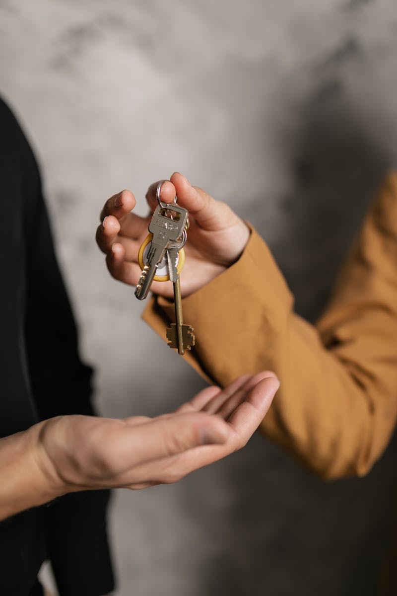 Two adults exchanging house keys, symbolic of property transfer or rental agreement. landlords